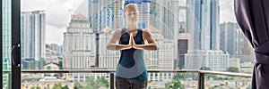 Young woman is practicing yoga in the morning on her balcony with a panoramic view of the city and skyscrapers BANNER