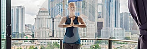 Young woman is practicing yoga in the morning on her balcony with a panoramic view of the city and skyscrapers BANNER, long format
