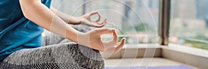 Young woman is practicing yoga in the morning on her balcony with a panoramic view of the city and skyscrapers BANNER, long format