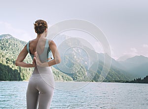 Young woman is practicing yoga at mountain lake