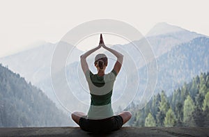 Young woman practicing yoga in mountains at sunset, meditation concept