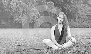 Young woman practicing yoga in nature. Sitting on green grass.