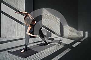 Young woman practicing yoga poses in an urban background on sunny day