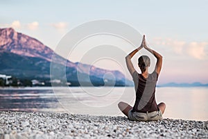 Young woman practicing yoga by the sea. Harmony, meditation, relaxation and healthy lifestyle concept