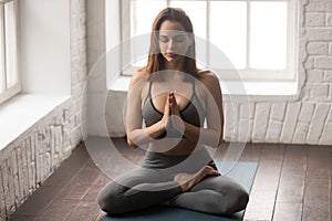 Young woman practicing yoga, sitting in Lotus pose, Padmasana exercise