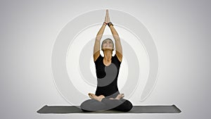 Young woman practicing yoga, sitting in a lotus position, meditating with closed eyes on white background