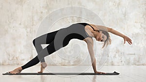 Young woman practicing yoga, standing in standing in Camatkarasana pose