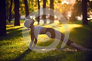 Young woman practicing yoga, stretching in Purvottanasana exercise - Upward Plank pose in the park at sunset