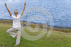 Young Woman Practicing Yoga By Tranquil Blue Lake