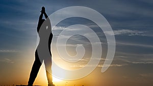 Young woman is practicing yoga in Tree Pose (Vrikshasana) pose at mountain lake