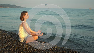 Young woman practises yoga and meditation at the beach. Sunset