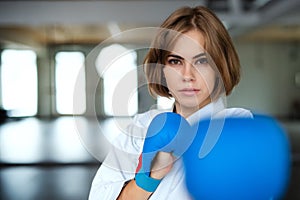 A young woman practising karate indoors in gym.