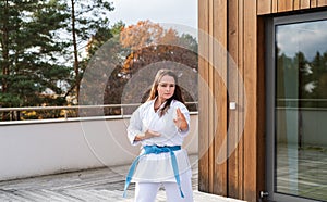 A young woman practising karate outdoors on terrace.