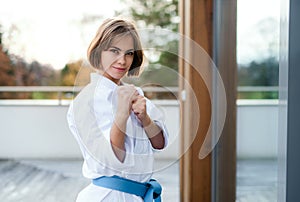A young woman practising karate outdoors on terrace.