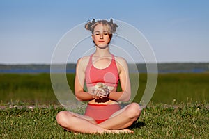 Young woman practising yoga meditation with her pet hedgehog on green grass at park in summer. Relax and harmony