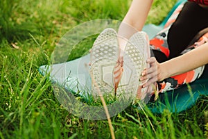 Young woman practising yoga in the open air in the nature on the grass on the sunny day. Outdoor sports. Exercises for tonus,