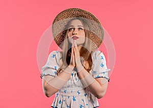 Young woman praying, begs to apologize her, she is guilty. Pink background.