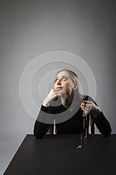 Young woman is praying with rosary beads