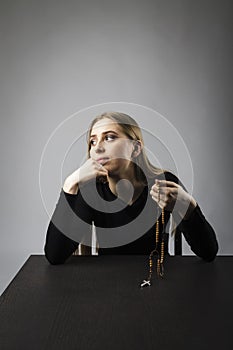 Young woman is praying with rosary beads