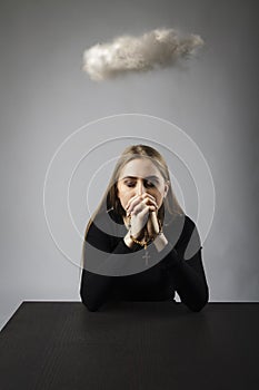 Young woman is praying with rosary beads and cloud