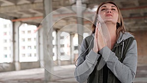 A young woman prays to God with folded hands. The concept of faith in the religion of Christianity