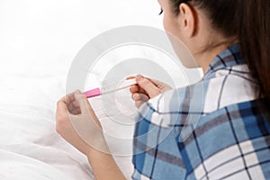 Young woman with pregnancy test on bed. Gynecology and childbirth