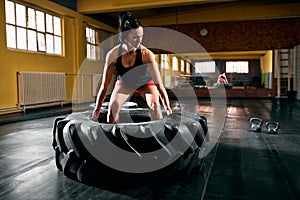 Young woman prepare to lift big tire