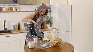 Young woman prepares dough mixing ingredients in the the bowl using whisk in the kitchen. Homemade food. Slowmotion shot