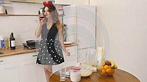 Young woman prepares dough mixing ingredients in the the bowl using whisk in the kitchen. Homemade food. Slowmotion shot