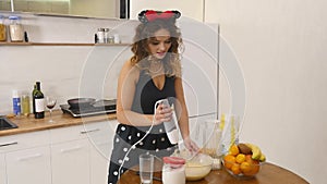 Young woman prepares dough mixing ingredients in the the bowl using whisk in the kitchen. Homemade food. Slowmotion shot