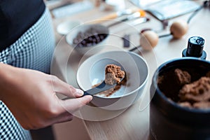 A young woman preparing chocolate cream with natural ingredients for body treatment. Body care concept