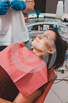 A young woman is preparing for a dental examination by a dentist, the patient is sitting in a dental chair. Happy patient in a