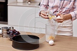 young woman preparing dough and cracking eggs