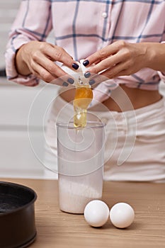 young woman preparing dough and cracking eggs