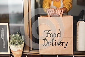 Young woman preparing food delivery inside ghost kitchen during quarantine isolation time - Take away meal for online order -