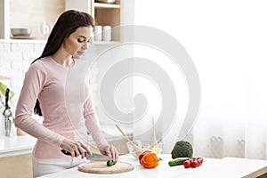 Young woman preparing fresh salad at kitchen