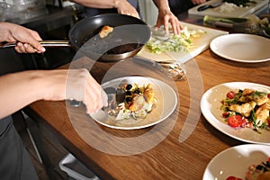 Young woman preparing tasty meat and salad during cooking classes in restaurant kitchen