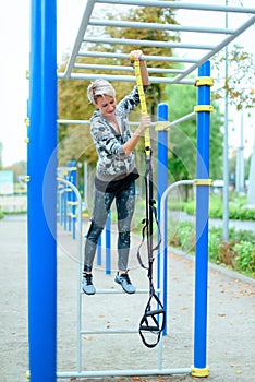 Young woman preparing for training in park with TRX loops  outdoor ,