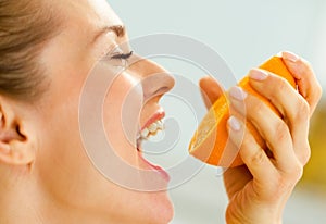 Young woman pressing orange juice in mouth