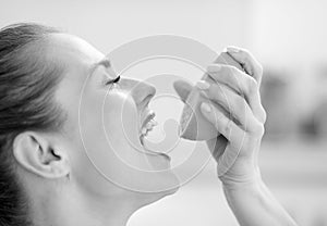 Young woman pressing orange juice in mouth