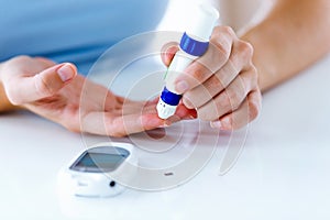 Young woman pricking herself to get a blood sample and perform a glucose test.