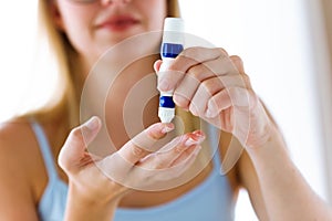 Young woman pricking herself to get a blood sample and perform a glucose test.