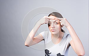 Young Woman Pricking Pimple on Forehead Seriously photo