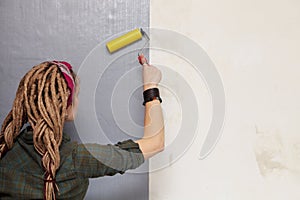Young woman primed the wall. photo