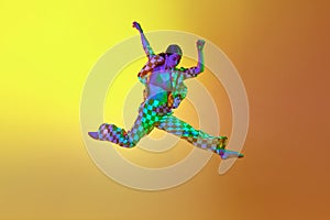 Young woman, professional contemporary dancer in motion, in stylish clothes against gradient yellow orange background in