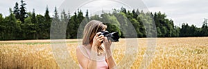Young woman with professional dslr camera taking photos outside in beautiful nature