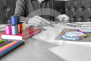 Young woman professional Fashion designer working and drawing sketches on the table