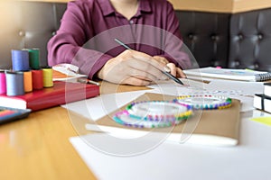 Young woman professional Fashion designer working and drawing sketches on the table