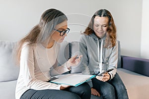 Young woman professional psychotherapist talking with teen girl in office. Mental health of child in adolescence