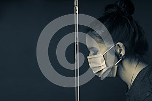 Young woman in profile behind a protective glass with respirator to protect against the corona virus and eyes closed